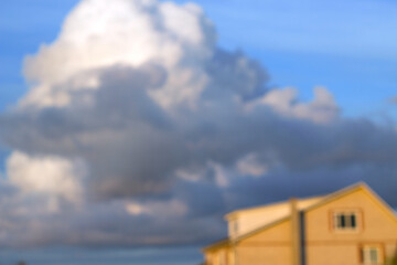 unfocused yellow brick house and dark sormy cloud in blue evening sky
