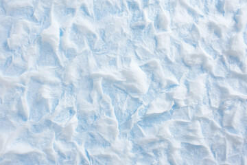 Obraz premium Textured snow surface, soft uneven layers with faint blue shadows and shimmering highlights