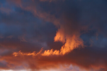 Dynamic sunset sky featuring vibrant orange and dark blue clouds at twilight