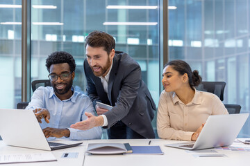 Diverse business team collaborating on project in modern office. Group of professionals using...