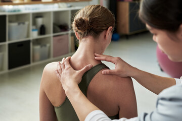 Physiotherapist giving patient spinal adjustment during therapy session in modern clinic. Patient...