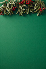 Christmas green background with holly and red berries. Flat lay, top view, copy space