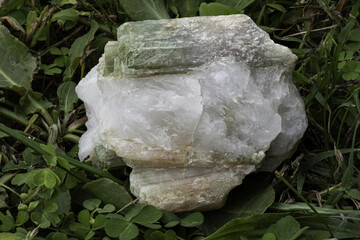 Close-up view of a vibrant, prismatic tourmaline crystal resting in a clear quartz matrix,...