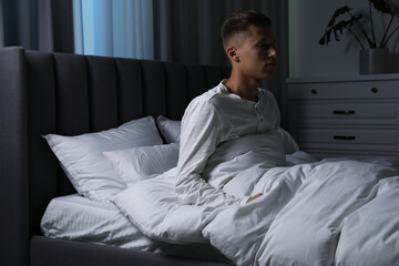 Young man suffering from sleepwalking on bed at home