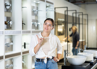 in plumbing department, middle-aged woman thought about choosing suitable bathroom for new apartment