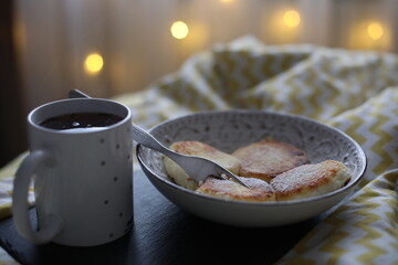 A warm and cozy scene of a person enjoying delicious homemade cheese pancakes and a cup of hot tea...