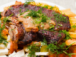 Dinner with premium t bone steak, fried potatoes chips with ridge, fresh salad with feta cheese on white plate and light color table cloth. Large portion of food with high quality products.