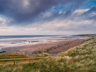 Stunning Fanore beach in county Clare, Ireland. Popular travel and tourist hotspot with amazing Irish nature scenery view. Sandy beach with rocks, powerful ocean with waves and dramatic sky.