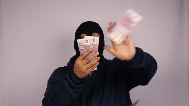close up on the thief fanning out his bundles of 500 euro banknotes and wearing a jacket with a white background.
