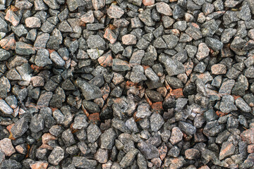Close up photo of macadam gravel on the ground. Some of the stones are colorful.