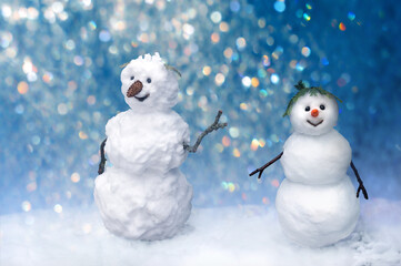 Old and young snowman smiling on New Year's background of colored lights