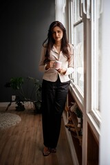 Businesswoman with coffee by a window