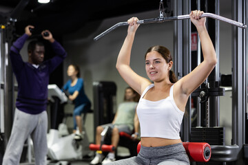 Caucasian woman training on lat pull down machine in gym