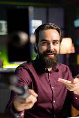 Internet star using smartphone on selfie stick to film vlog channel intro for online streaming platforms. Content creator greets viewers, presenting today video topic, recording with phone camera