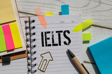 text IELTS on wooden cubes. bright yellow surface. wooden sphere balls among the wood cubes