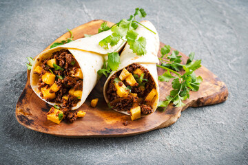 Mexican style burritos - tortilla wrap with spicy minced meat, vegetables and pineapples served as...