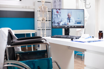 Doctors office with wheelchair friendly desk and computer screen shows medical consultation in...