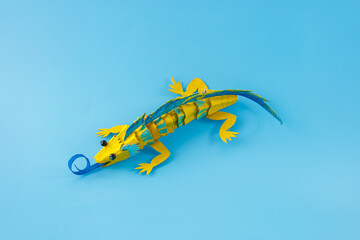 an upcycled egg box lizard. blue background , artistic creativity, unique and imaginative,