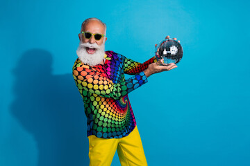 Portrait of extravagant charismatic aged man hold disco ball wear shirt isolated on blue color...