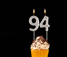 Birthday cupcake on black background - Number 94 shaped candles.