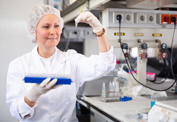 Portrait of focused woman scientist working in medical science laboratory, performing laboratory experiment and looking at test tube © JackF
