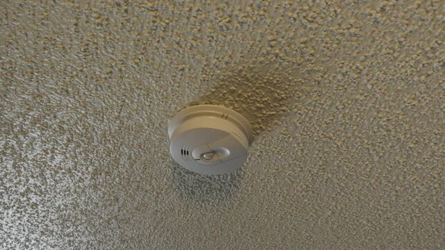 Fire alarm mounted on popcorn ceiling interior for apartment safety and design