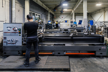 Factory worker working on lathe in metalworking workshop