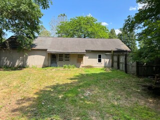 Obraz premium Very Old Wooden House with Weathered Exterior in a Fenced Backyard Surrounded by Overgrown Vegetation