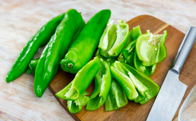 Fresh peppers on a wooden chopping board while cooking. Close-up image