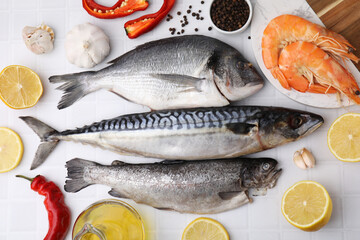Fresh raw sea food and products on white tiled table, flat lay