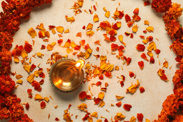 Diwali celebration. Diya lamp and beautiful flowers on light background, top view