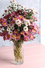 Vase with beautiful flowers on pink wooden table, closeup