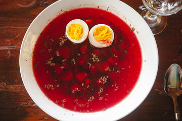 Red borscht soup with cut hard-boiled egg on a wooden table close-up