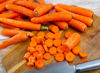 Fresh carrots on a wooden chopping board while cooking. Close-up image