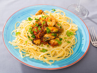 Close up of tasty warm pasta with shrimp and mussels, served with greens