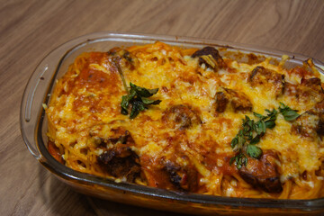 Close-up of delicious spaghetti with meatballs, topped with tomato sauce and grated cheese. The focus is on the texture of the pasta and meatballs, with a blurred background.