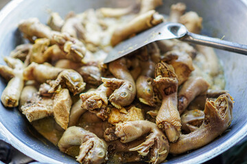 Close-up of a wok filled with a stew made with chicken feet. The chicken feet are cooked and seasoned. Delicious Chicken Feet Stew in a Wok