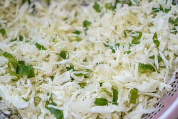 Close-up view of finely shredded cabbage mixed with chopped green onions. Looks appetizing and ready for cooking. Freshly Shredded Cabbage with Green Onions.