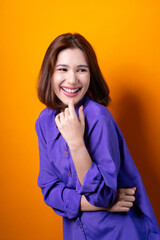 Portrait young cheerful asian woman wearing purple shirt happy smile isolated on yellow background.