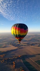Obraz premium A stunning real-life image of a colorful hot air balloon floating gently in the sky, with expansive landscapes stretching out below. 