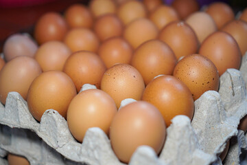 Close-up view of many fresh brown eggs arranged and stacked in a cardboard egg carton. A Carton of...