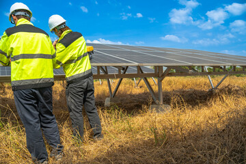 Team engineers in a high visibility jacket performs an inspection on the underside of a solar panel installation at a solar farm, emphasizing renewable energy infrastructure under bright skies.
