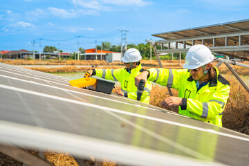 Team engineers in a high visibility jacket performs an inspection on the underside of a solar panel...