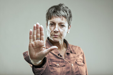 Serious mature woman making stop sign with hand