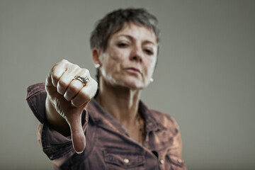 Mature woman showing thumbs down gesture expressing disapproval