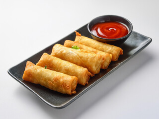 Chinese egg rolls with chili sauce on a white background