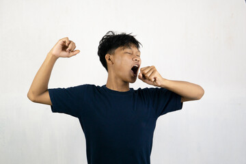 Asian man with a sleepy expression and yawning with messy hair. Wake up concept. Isolated on white...