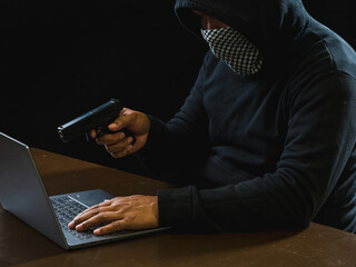 Hacker spy man one person in black hoodie sitting on table looking computer laptop used login...