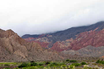 Paisaje con cerros coloridos bajo un cielo lleno de nubes