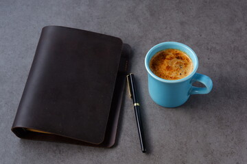ミルクを入れたコーヒー、カフェ・ラッテを飲みながら、茶色の革のシステム手帳でデスクワーク中のイメージ
